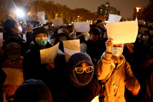 People hold white papers at a vigil to remember those affected by the Urumqi fire as the coronavirus disease continues to spread in Beijing, China, November 27, 2022.
