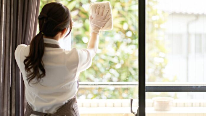 Asian woman cleaning the living room window